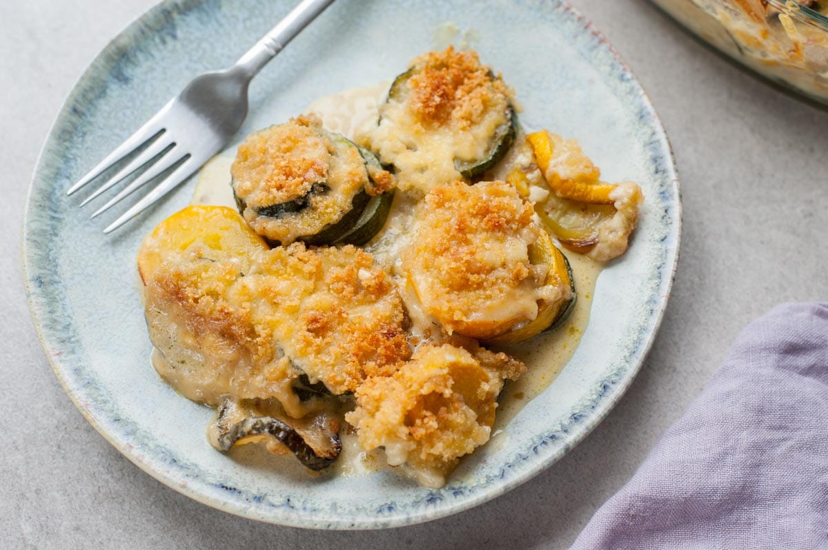 one serving of zucchini gratin on a light blue plate, fork on the side