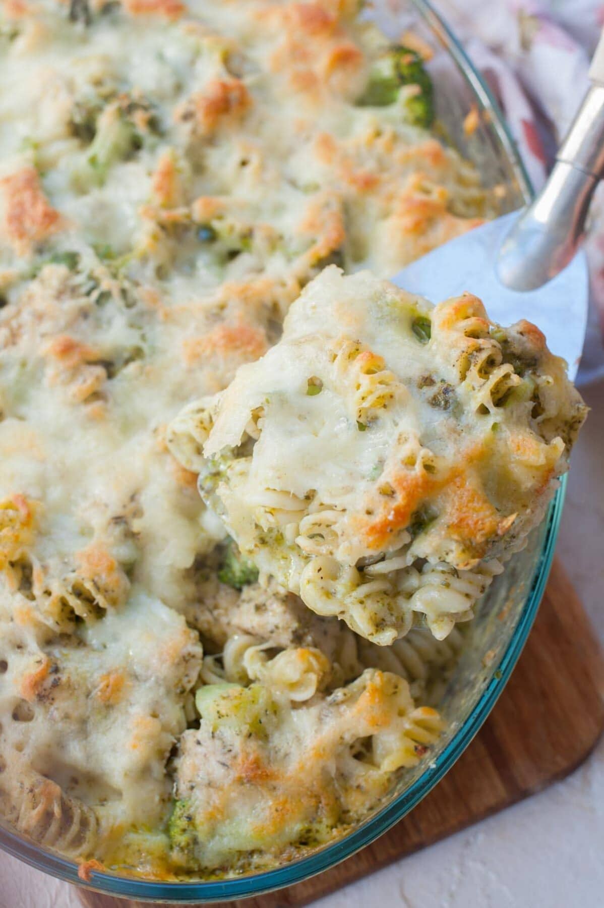 Chicken pesto bake on a large spatula. Casserole dish in the background.