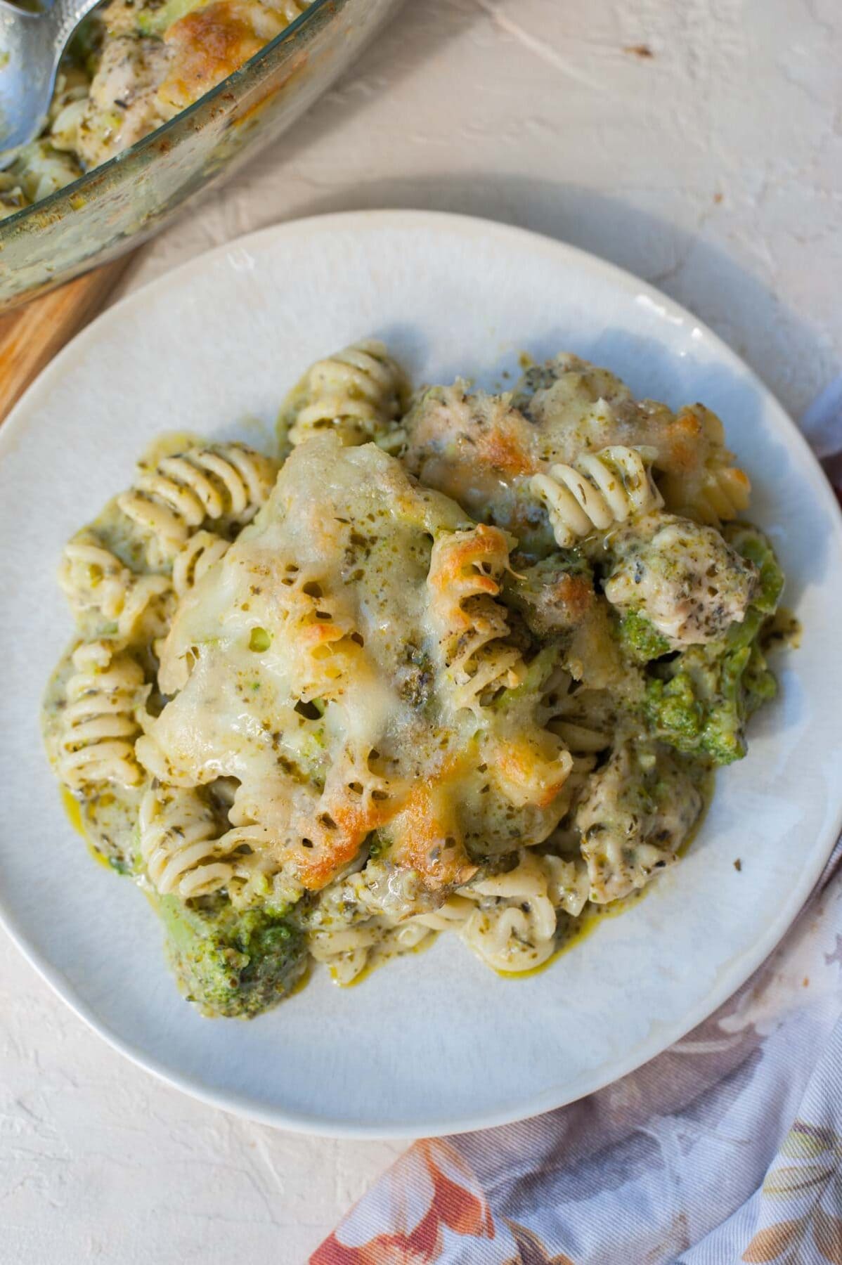 A serving of pesto pasta chicken bake on a white plate.