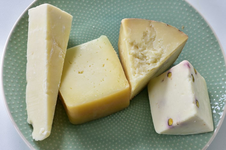 Different kinds of Pecorino cheese on a green plate.