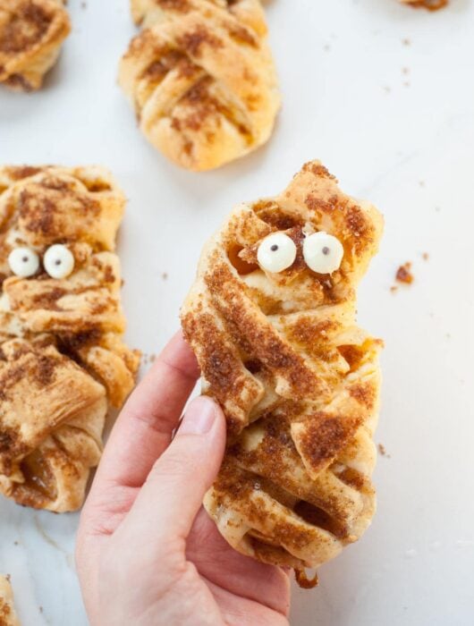 Mummy apple hand pies held in a hand.