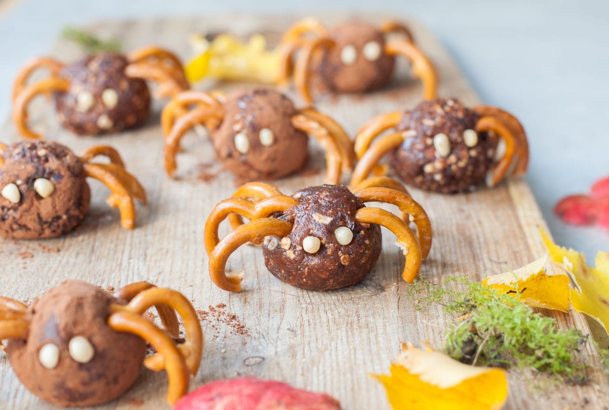 Pretzel spiders on a chopping board. Leaves scattered around.