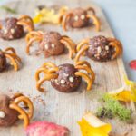 Pretzel spiders on a chopping board. Leaves in the background.