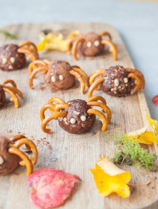Pretzel spiders on a chopping board. Leaves in the background.