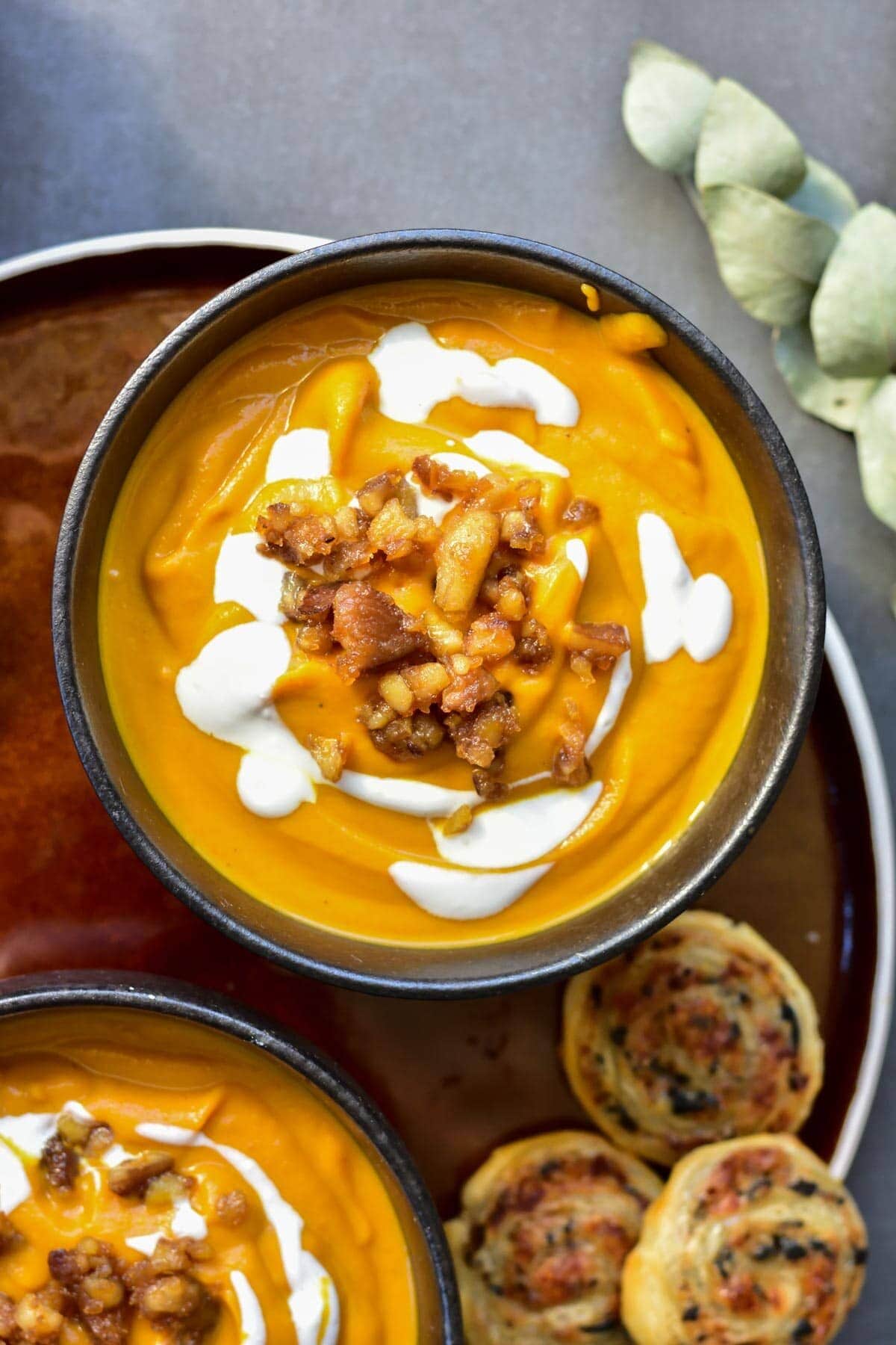 Pumpkin chestnut soup in a black bowl topped with caramelized chestnuts and yogurt.