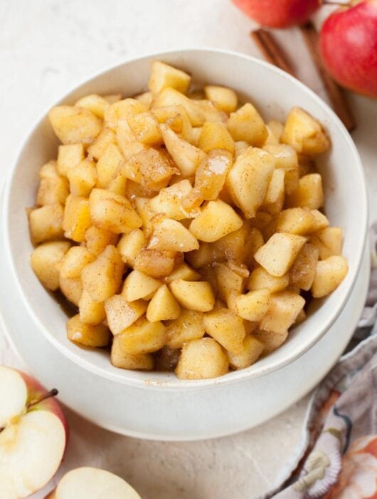 Sauteed cinnamon apples in a white bowl.