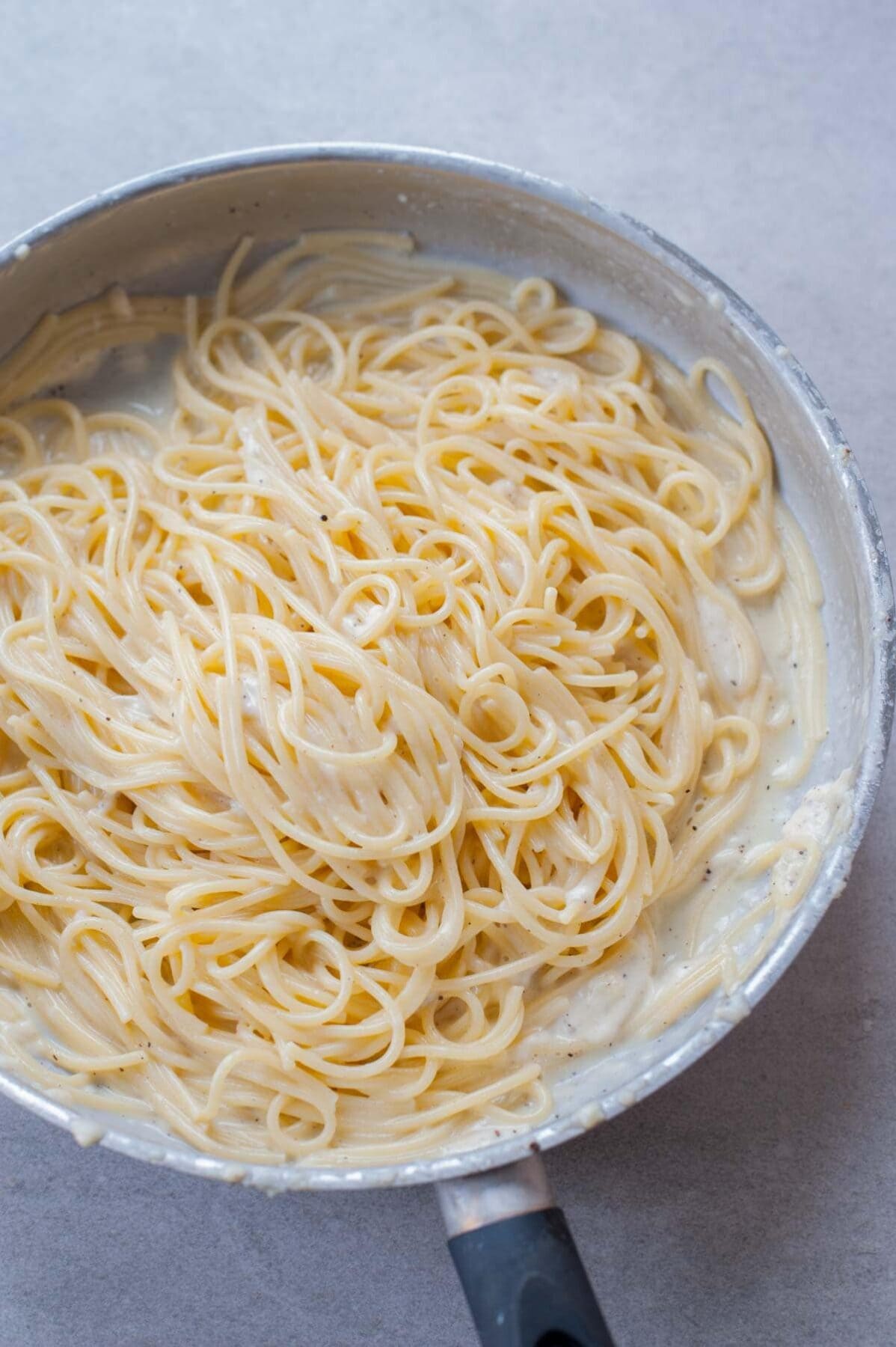 Spaghetti cacio e pepe in a metal pan.