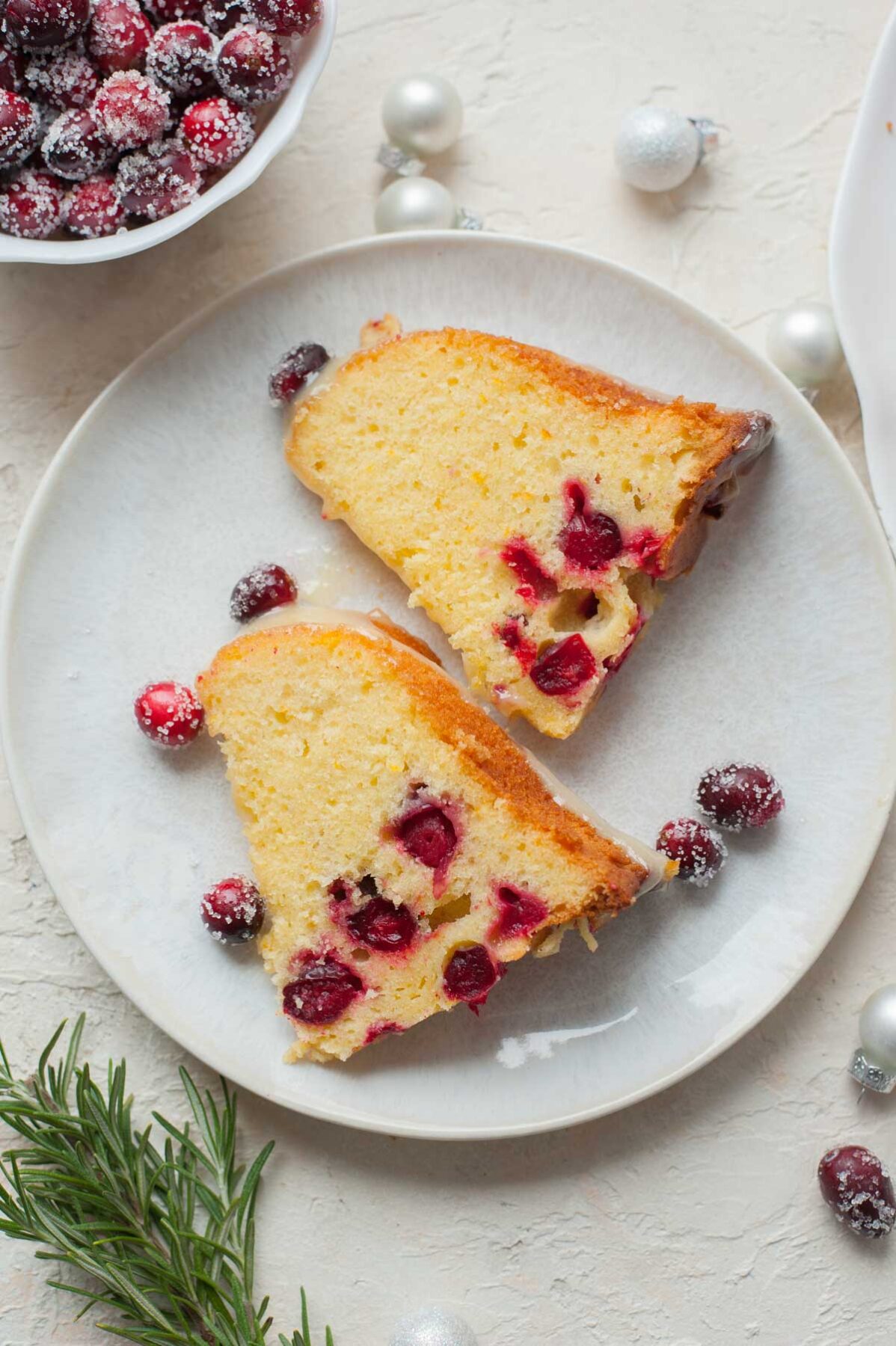 Two slices of cranberry orange bundt cake on a white plate.