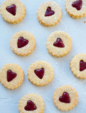 Raspberry Linzer cookies on a blue background.