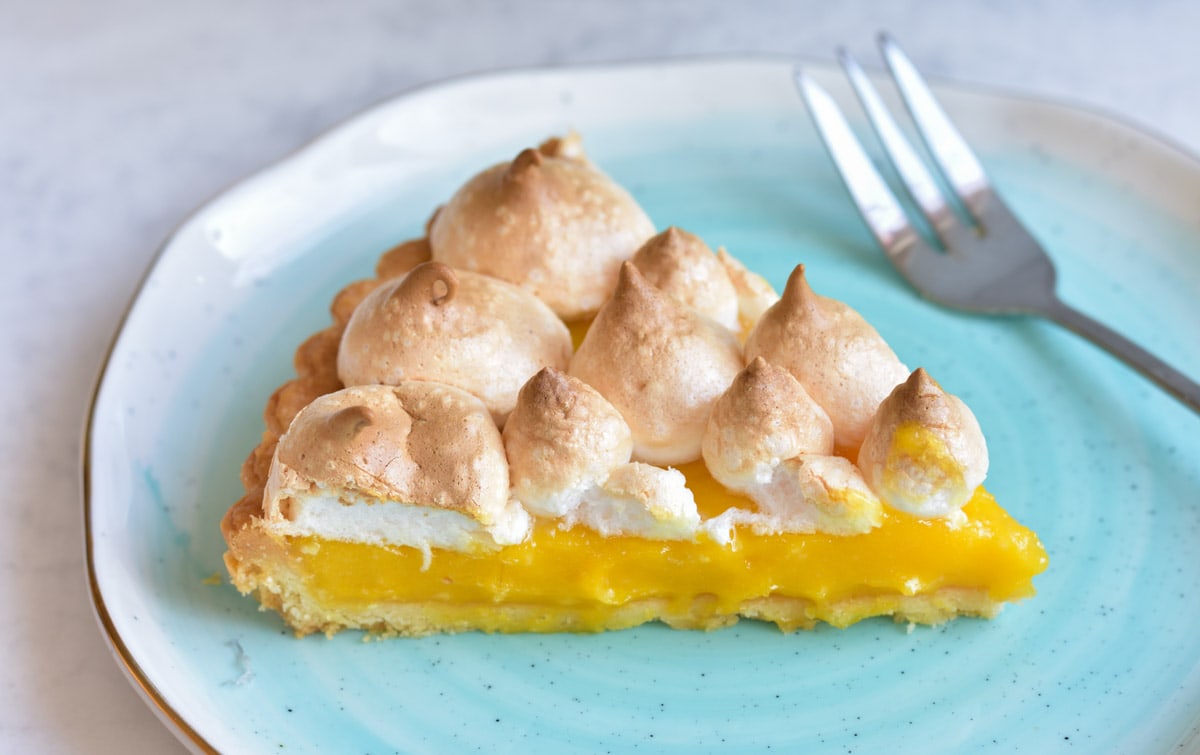 A piece of passion fruit tart on a blue plate.