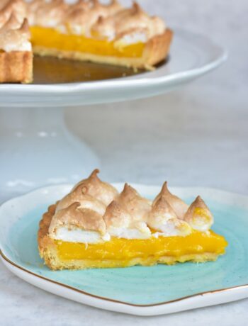 Passion fruit tart topped with meringue on a blue plate.