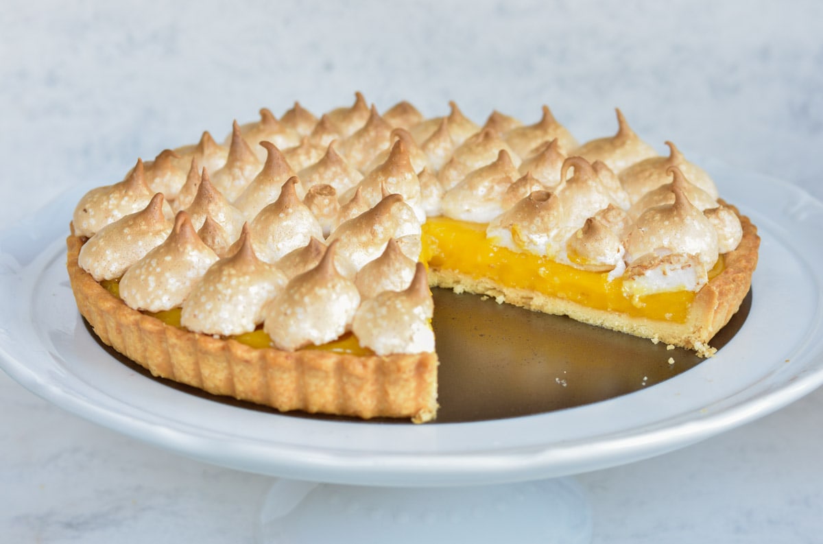 Passion fruit tart on a white cake stand.