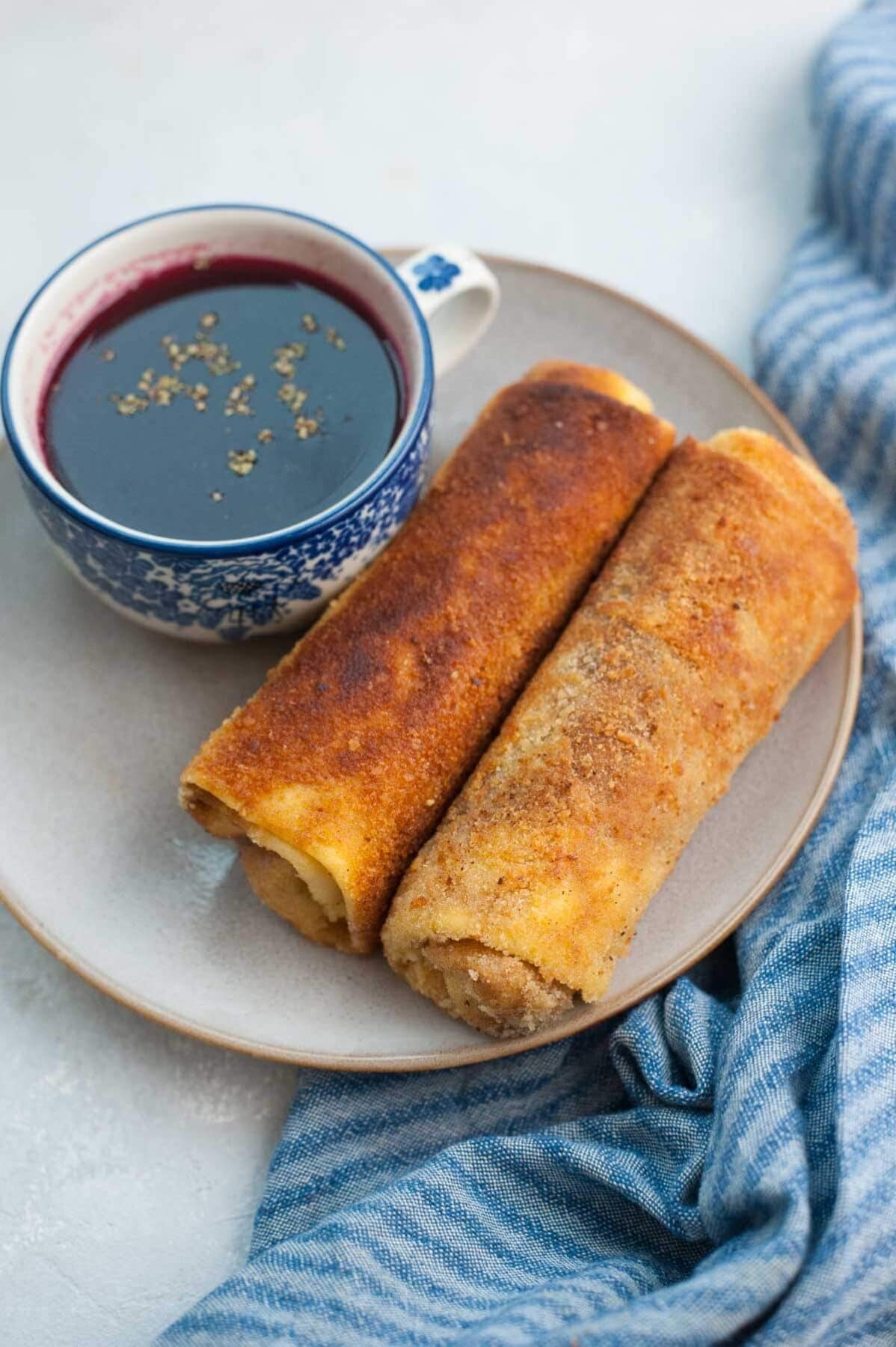 Polish croquettes on a brown plate with a small cup of borscht soup.