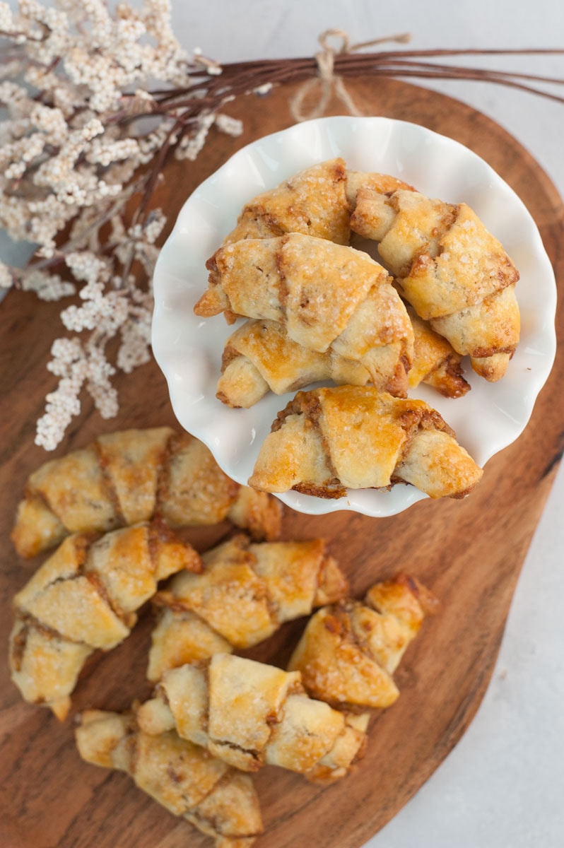 Rogaliki cookies on a chopping board and a white cake stand.