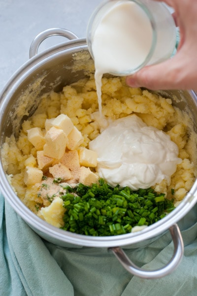 Milk is being added to mashed potatoes in a pot.