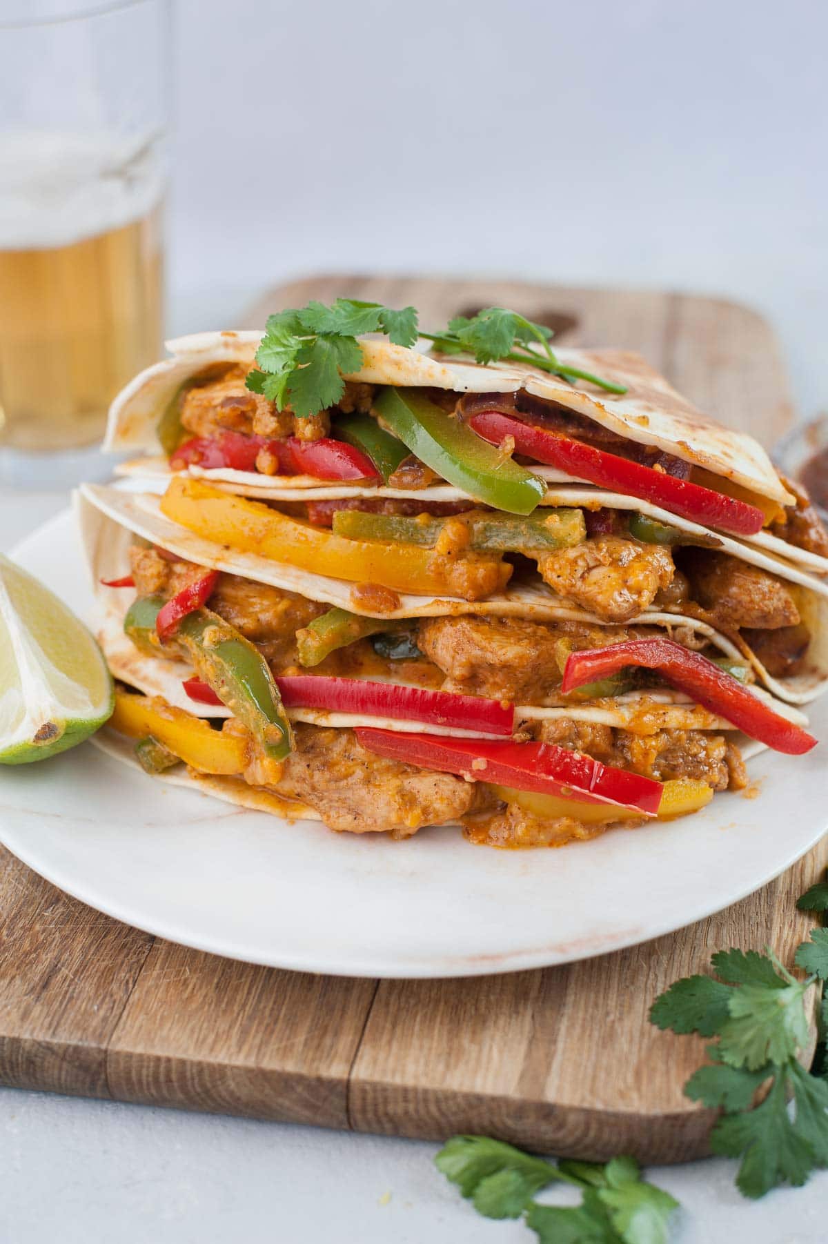 Chicken fajita quesadillas on a wooden boards topped with cilantro leaves.