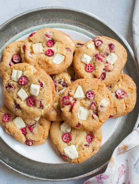 Fresh cranberry white chocolate cookies on a silver tray.