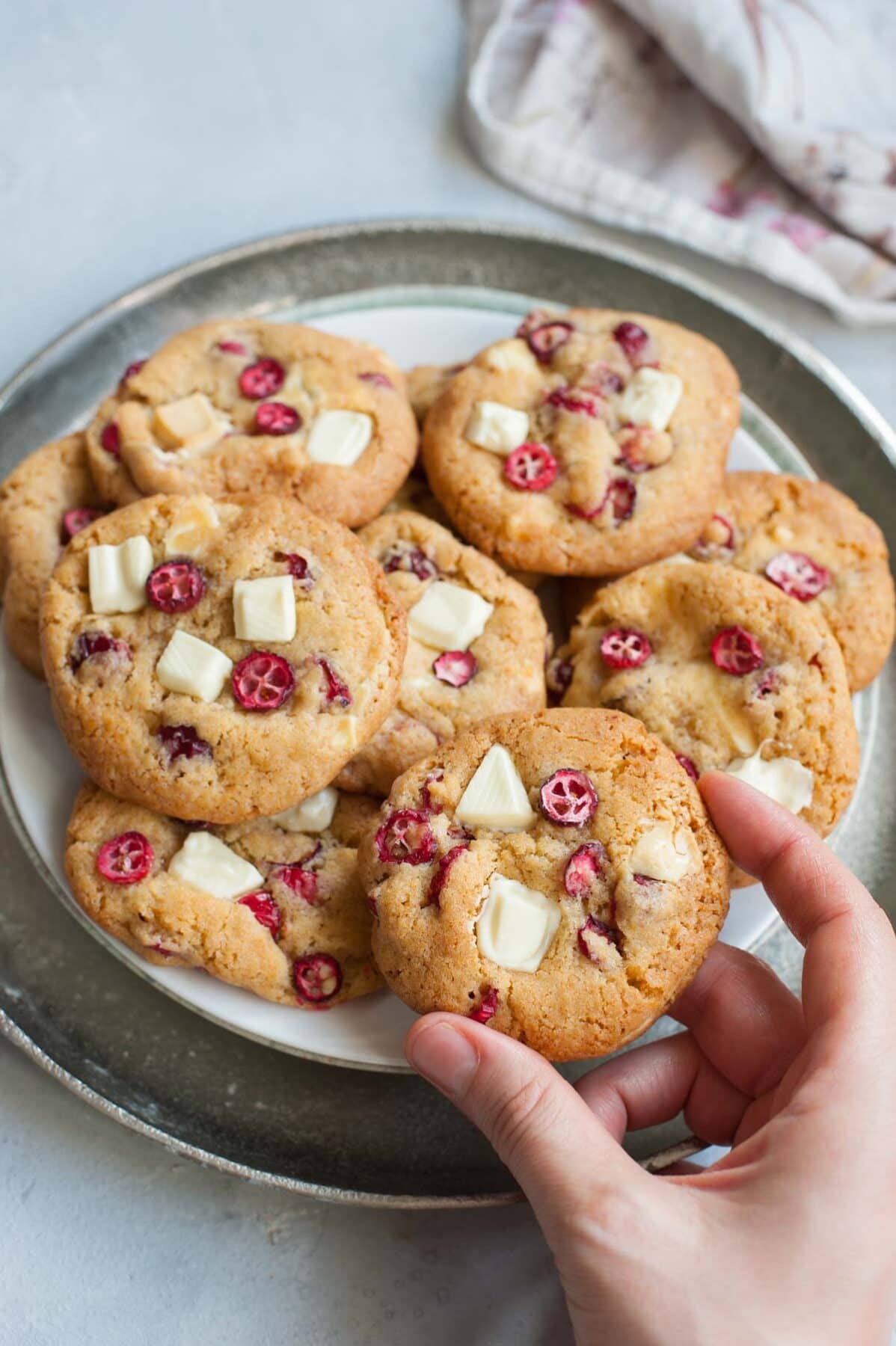 Fresh cranberry white chocolate cookie held in a hand.