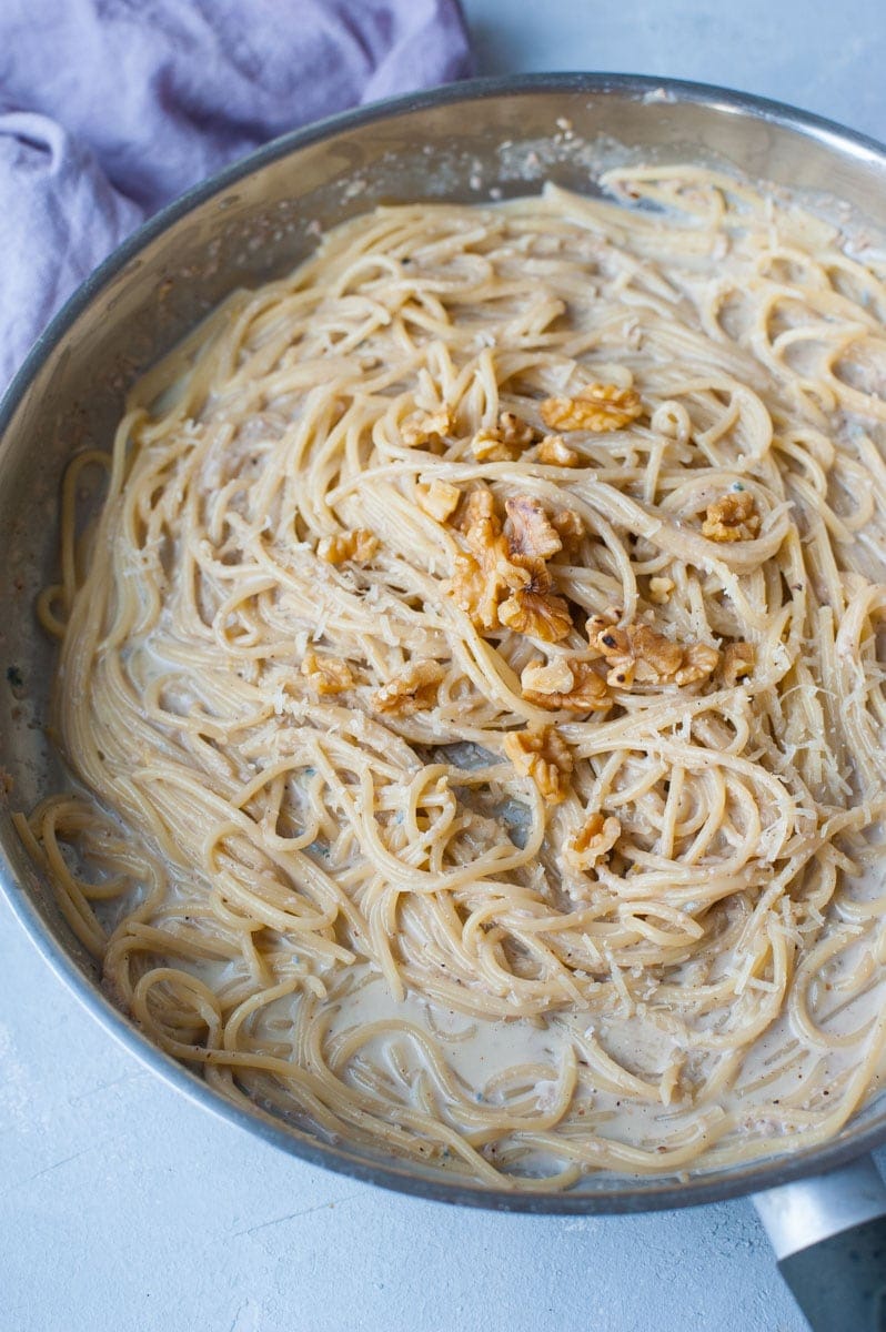 Gorgonzola walnut pasta in a frying pan topped with walnuts.