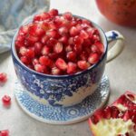 Pomegranate seeds in a blue cup.