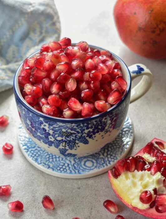 Pomegranate seeds in a blue cup.