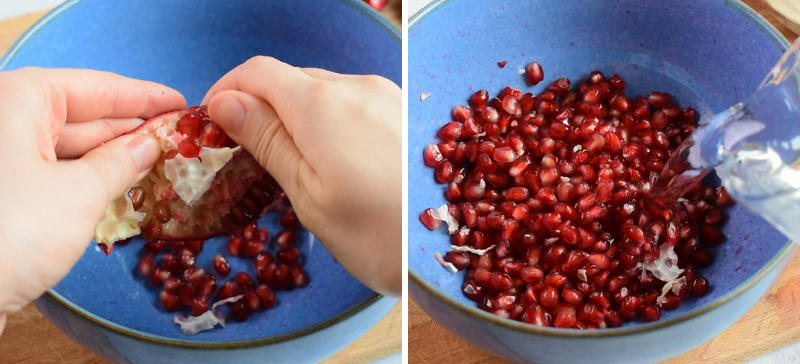 Pomegranate segments are being de-seeded. Water is being added to pomegranate seeds in a blue bowl.