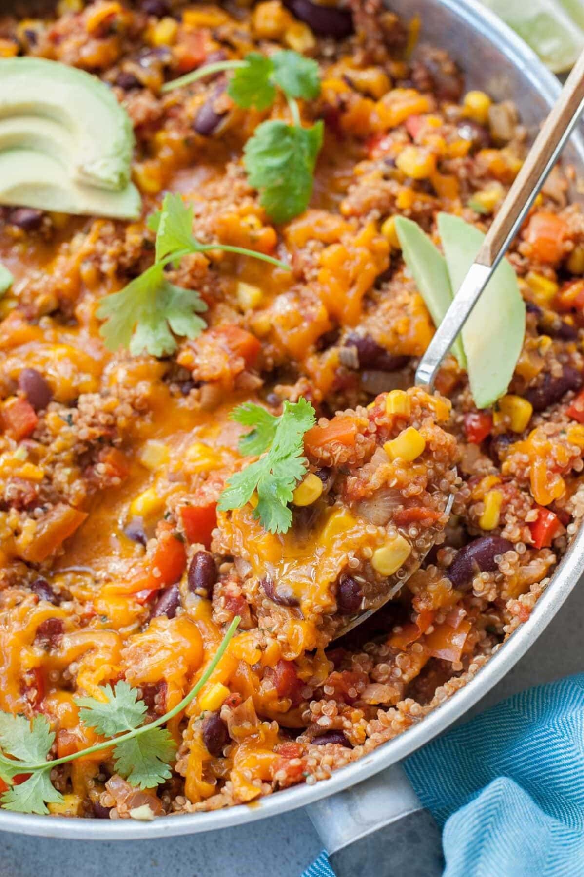 Mexican quinoa in a frying pan topped with coriander and avocado.