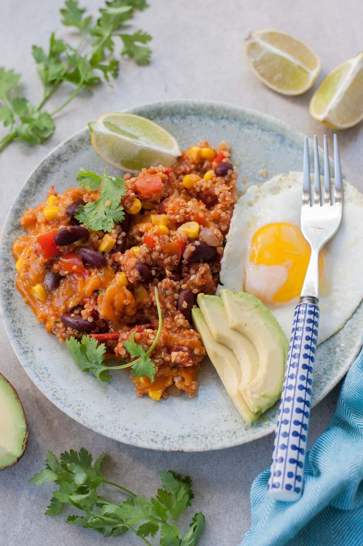 Quinoa po meksykańsku na zielonym talerzu z jajkiem sadzonym i awokado.