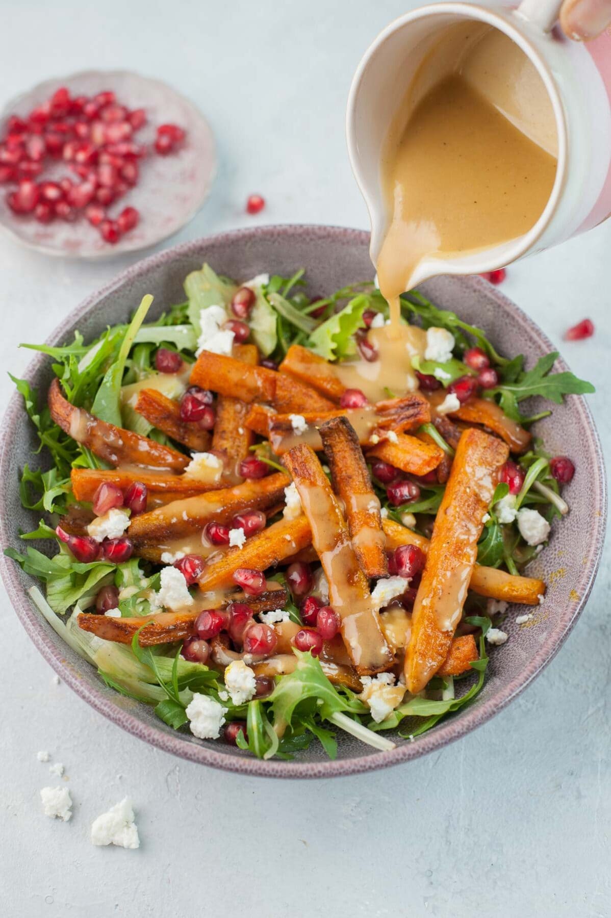 Peanut butter lemon dressing is being poured over roasted carrot salad.