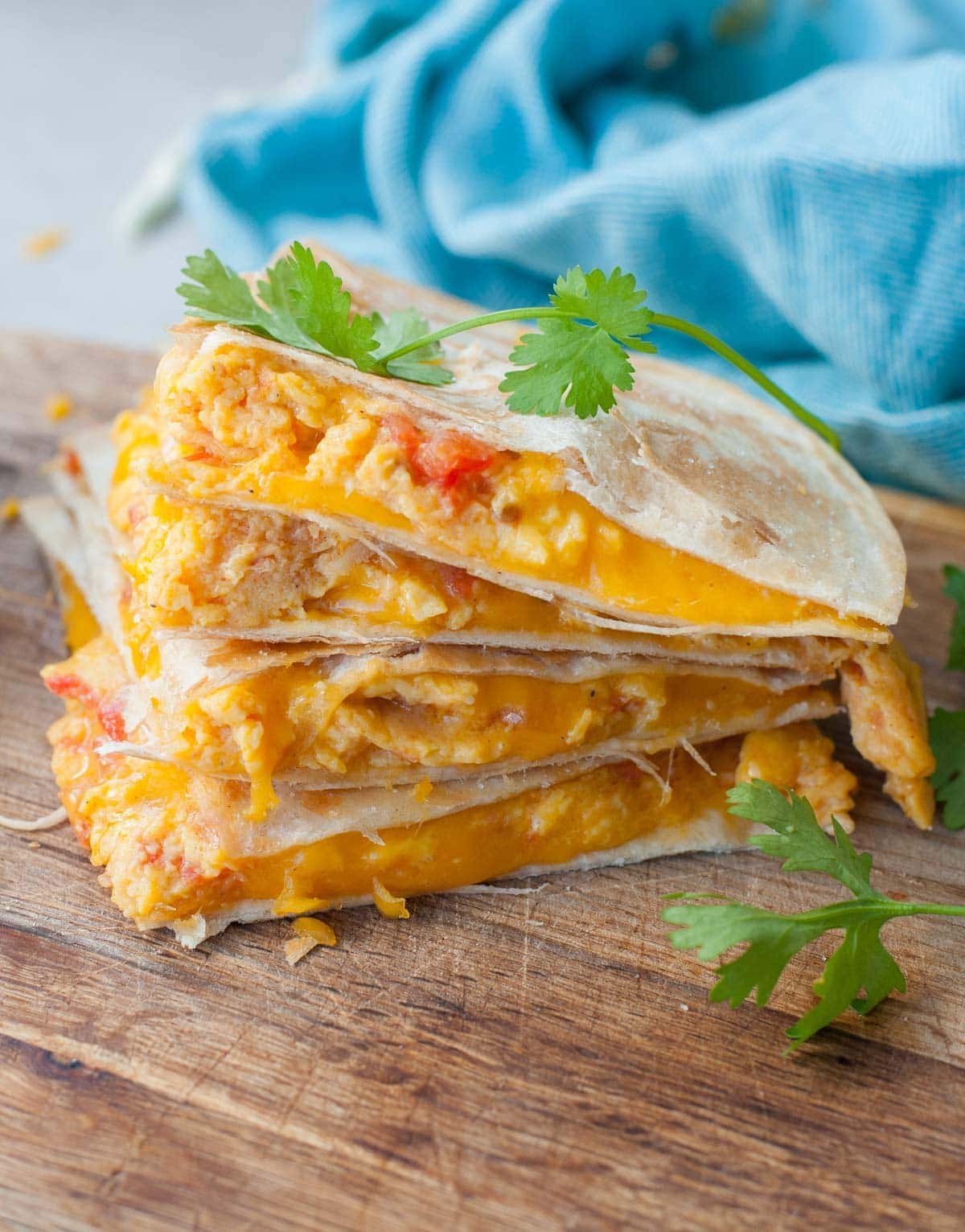 A stack of breakfast quesadillas on a wooden board.