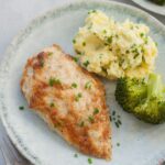 Parmesan mayo chicken on a green plate with mashed potatoes and broccoli.