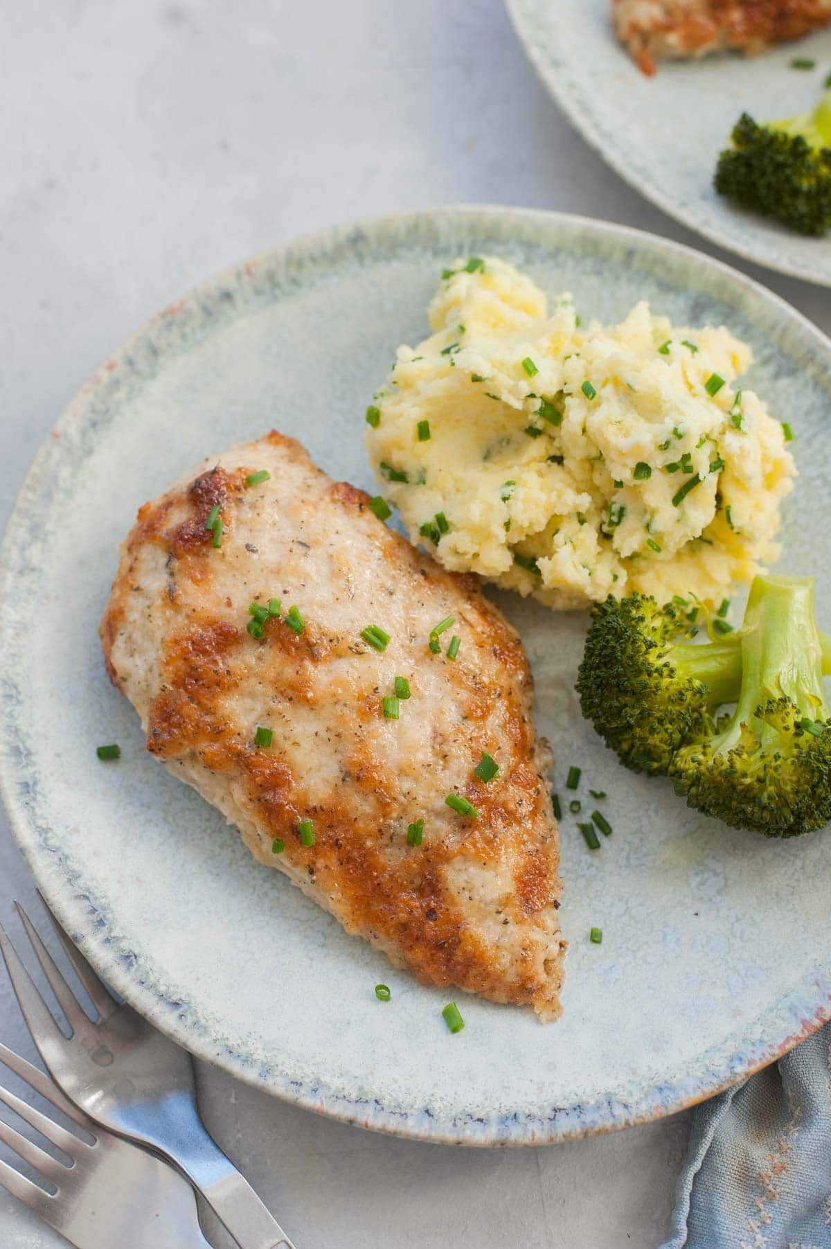 Parmesan mayo chicken on a green plate with mashed potatoes and broccoli.