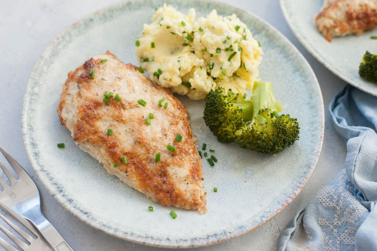 Parmesan mayo chicken on a green plate with mashed potatoes and broccoli.