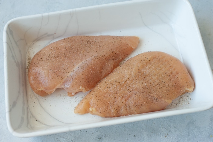 Two chicken breasts in a white baking dish.