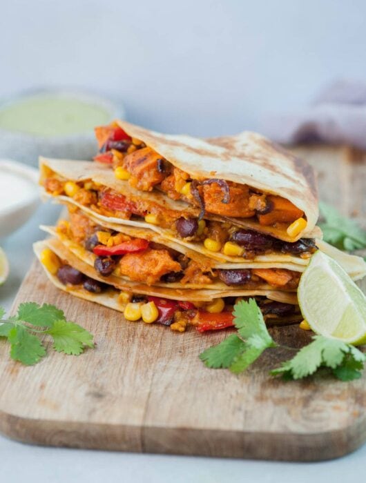 Vegetarian quesadillas on a wooden chopping board.