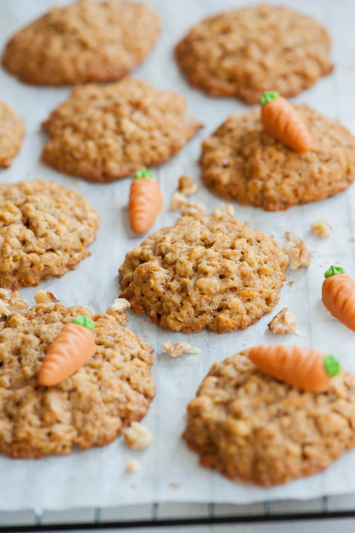 Carrot cake cookies on a piece of parchment paper, topped with marzipan carrots and walnuts.