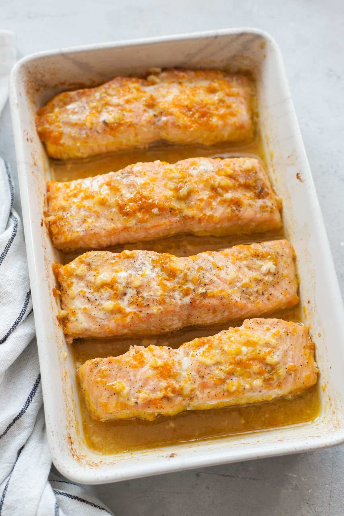 Baked orange maple salmon in a white baking dish.