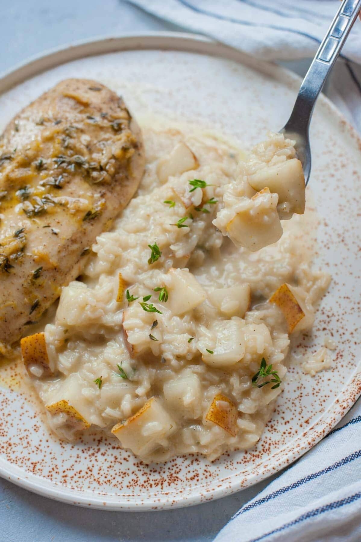 Pear risotto with gorgonzola on a plate with chicken breast on the side.