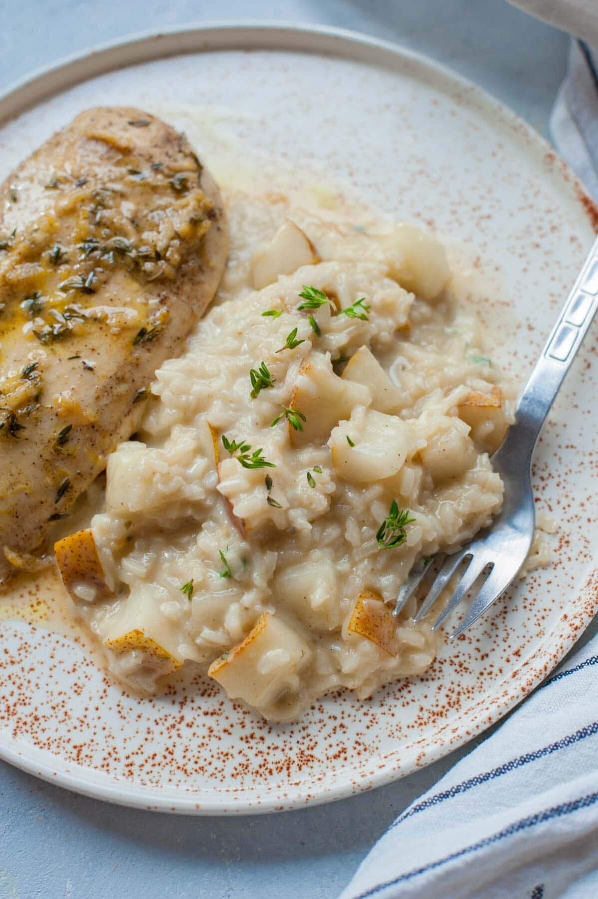 Pear risotto sprinkled with thyme on a white plate.