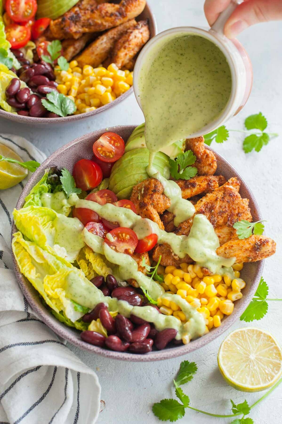 Avocado cilantro lime dressing is being poured over southwest chicken salad.