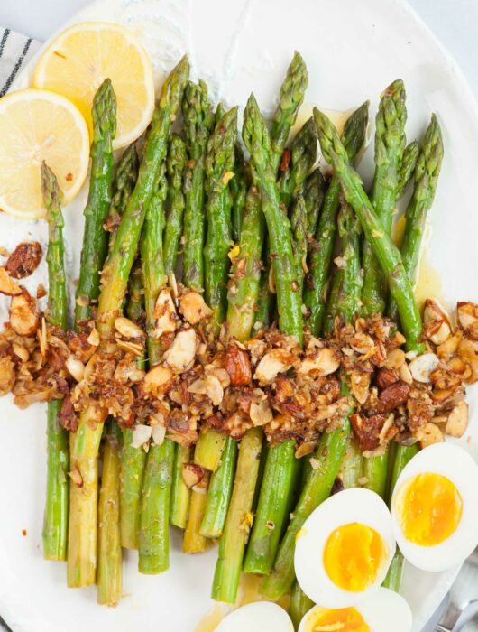 Asparagus almondine topped with almonds garlic. Hard-boiled eggs and lemon slices on the side.