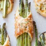 Asparagus in puff pastry with ham and cheese on a grey background.