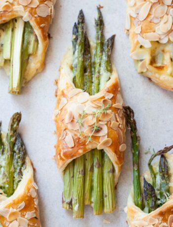 Asparagus in puff pastry with ham and cheese on a grey background.