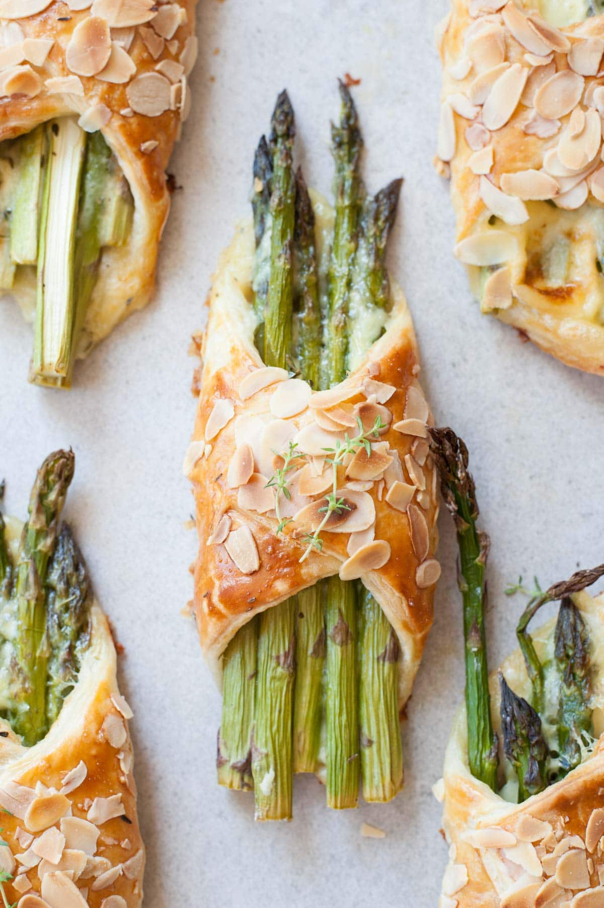 Asparagus in puff pastry with ham and cheese on a grey background.