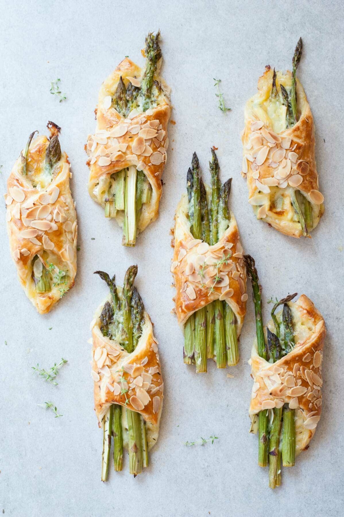 Puff pastry asparagus bundles on a grey background.