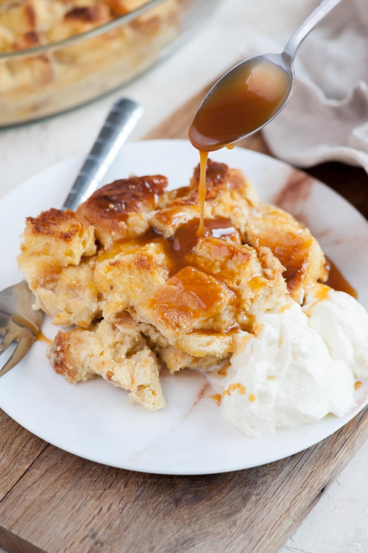 Brioche bread pudding is being drizzled with salted caramel sauce.