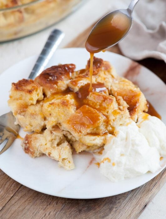 Brioche bread pudding is being drizzled with caramel sauce.