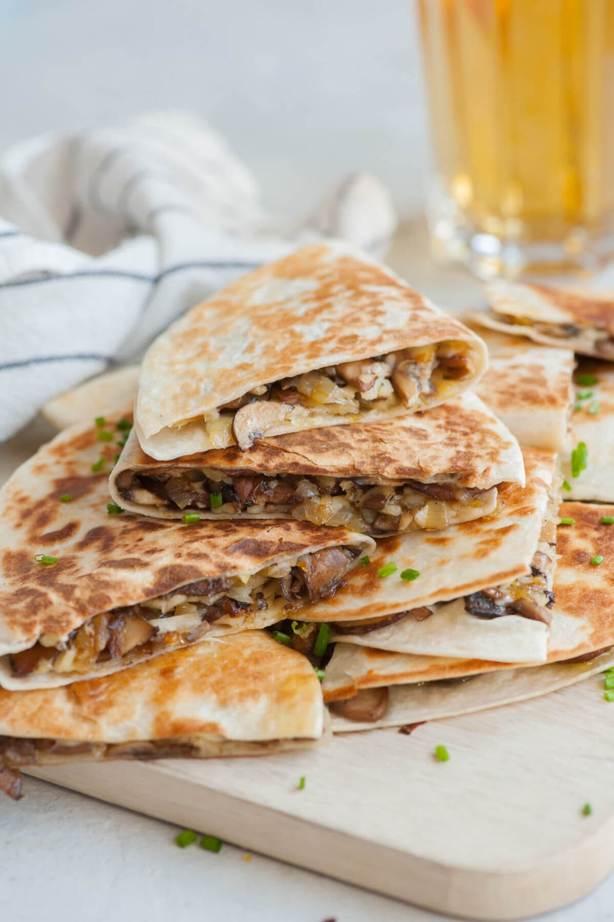 A stack of mushroom quesadillas on a beige wooden board.