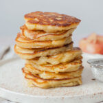 A stack of apple pancakes on a white plate.