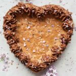 Heart-shaped chocolate chip cookie cake on a grey background.